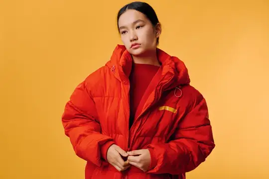 Портрет молодой девушки-модели в красном стеганом пальто с высоким воротником