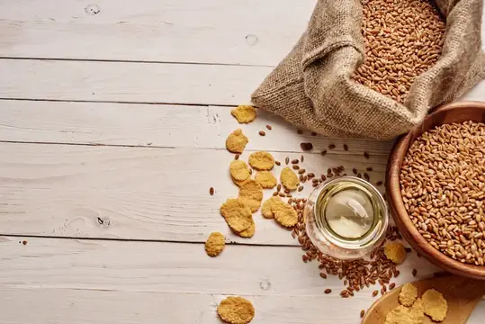 Мешок и миска с пшеничными зёрнами на светлом деревянном столе