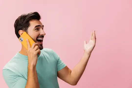 Улыбающийся бородатый мужчина с желтым телефоном на розовом фоне