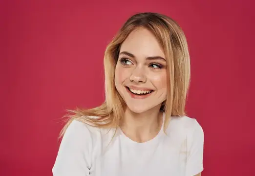 Улыбающаяся блондинка в белой футболке на красном фоне