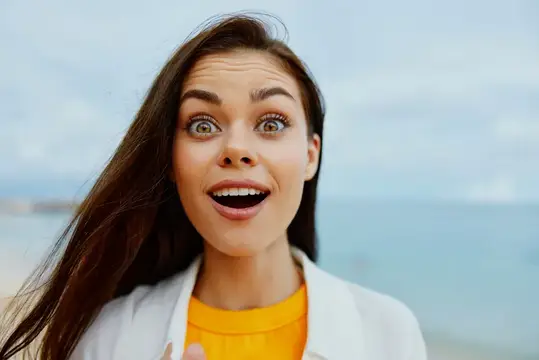 Удивлённая темноволосая девушка с открытым ртом на фоне моря