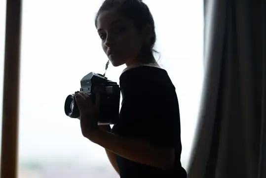 Молодая женщина с пленочной камерой у окна в silhouette