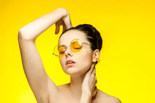 Молодая женщина в желтых круглых очках на ярко-желтом фоне