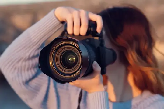 Девушка фотографирует на камеру с крупным объективом