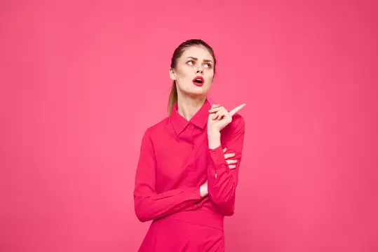 Женщина на розовом фоне в модной одежде, с ярким макияжем и прической, модель, свободное пространство