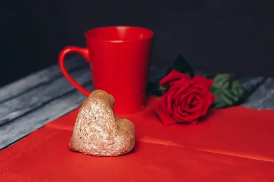 Красная кружка, роза и печенье-сердце на романтическом столе