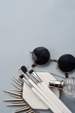 Круглые солнцезащитные очки, кисти и клатч с шипами на сером фоне