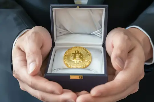 Мужские руки держат открытую коробочку с золотой биткоин-монетой