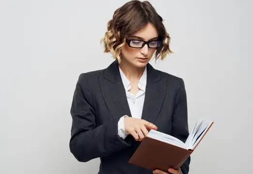 Деловая женщина с книгой в руках на светлом фоне, в классическом костюме, с модной прической