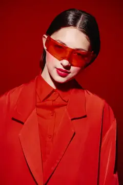 Азиатская девушка в красных очках и костюме на красном фоне