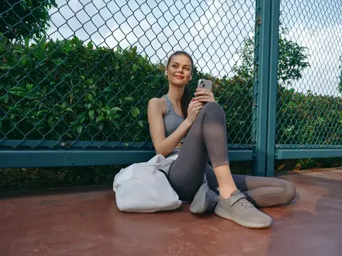 Спортивная девушка отдыхает на земле со смартфоном в руках