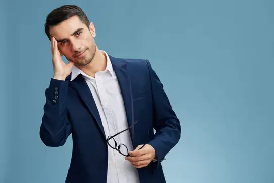 Уставший мужчина в синем костюме держится за голову на голубом фоне
