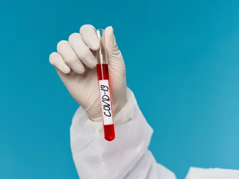 Рука в перчатке держит пробирку с кровью на анализ COVID-19