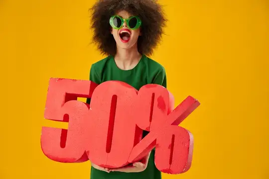 Кудрявая девушка в зелёных очках держит красную скидку 50%
