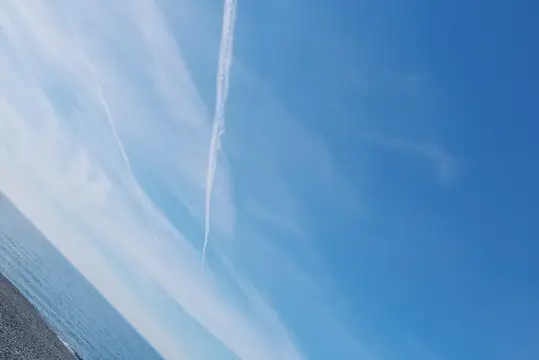 След самолёта в голубом небе над морем
