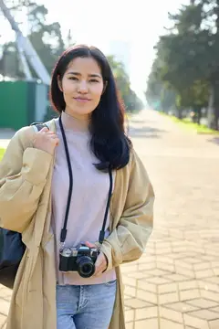 Азиатская девушка с пленочным фотоаппаратом на солнечной улице