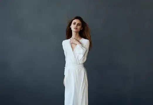 Красивая женщина в белом платье исполняет танец, модель