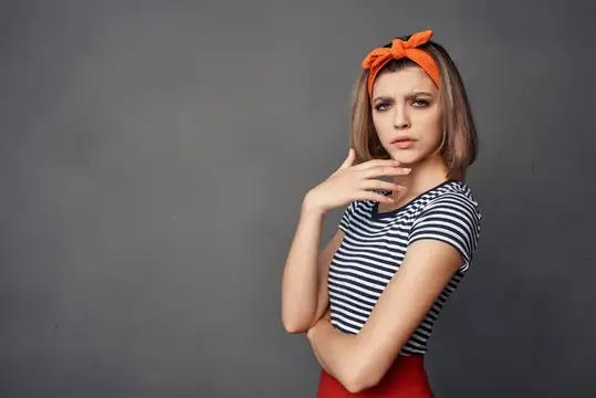 Молодая женщина с оранжевой повязкой на голове на сером фоне