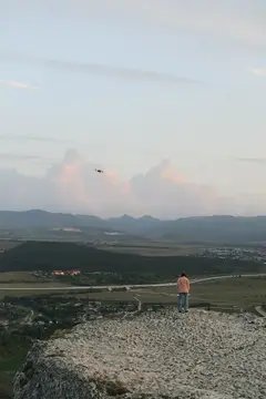 Мужчина стоит на скалистой вершине и смотрит на долину