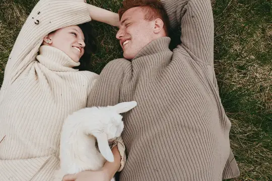 Расслабленная пара на открытом воздухе с козленком создает интимный, wholesome момент образа жизни на луговой траве