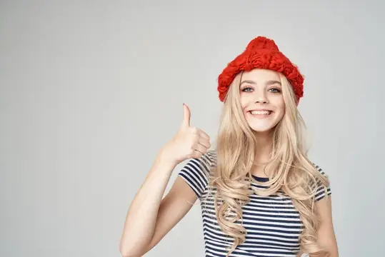 Красивая женщина в полосатой футболке и красной шляпе на светлом фоне
