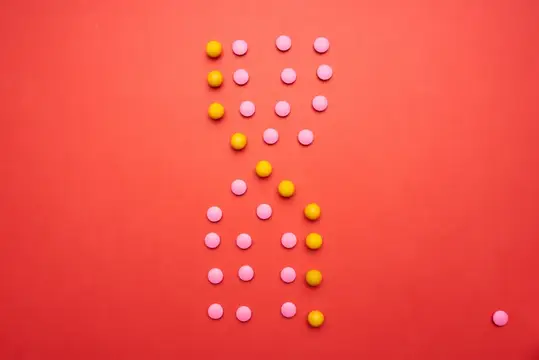Желтые и розовые круглые конфеты на красном фоне