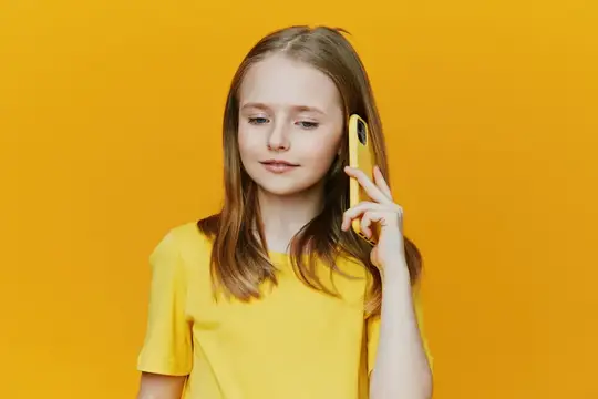 Светловолосая девочка-подросток разговаривает по телефону на жёлтом фоне