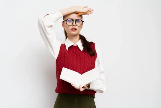 Уставшая девушка в очках с книгой держится за голову на белом фоне