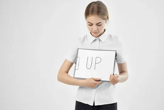 Молодая женщина в белой рубашке держит табличку с надписью UP