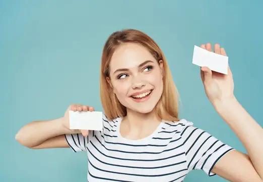 Улыбающаяся блондинка с двумя визитками на голубом фоне
