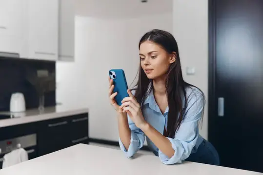 Молодая женщина с телефоном на светлой кухне