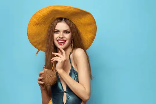 Улыбающаяся девушка в соломенной шляпе с кокосом на голубом фоне