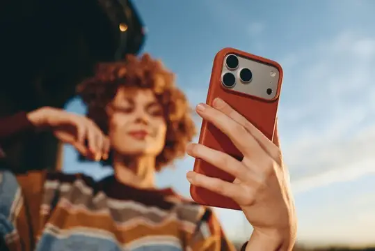 Рыжеволосая девушка делает селфи на смартфон в оранжевом чехле