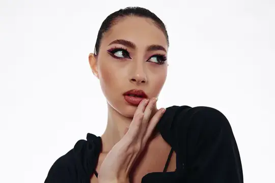 Азиатская девушка с ярким макияжем и чёрным топом на белом фоне