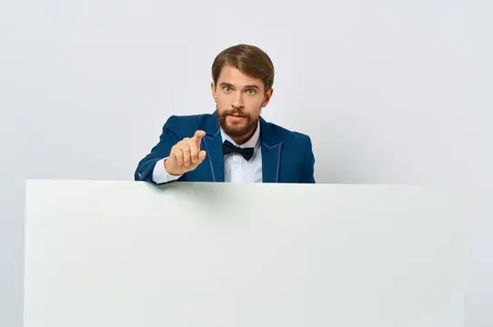 Мужчина в синем пиджаке и бабочке указывает пальцем на белый плакат