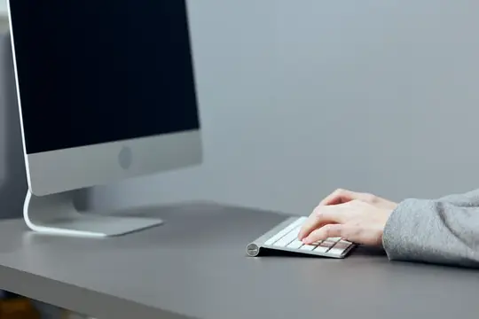 Руки человека печатают на клавиатуре перед монитором