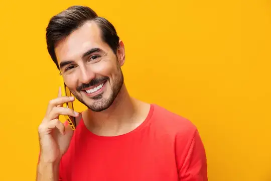 Портрет улыбающегося мужчины в очках на жёлтом студийном фоне