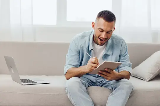 Улыбающийся мужчина с планшетом и ноутбуком на диване