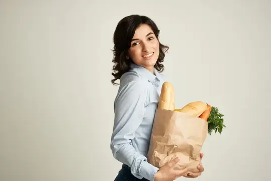 Брюнетка доставляет продуктовый пакет из супермаркета