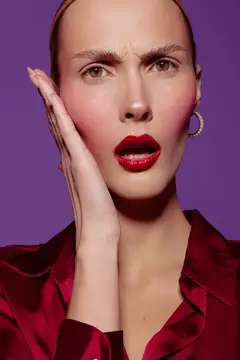 Удивлённая женщина с красной помадой на фиолетовом фоне