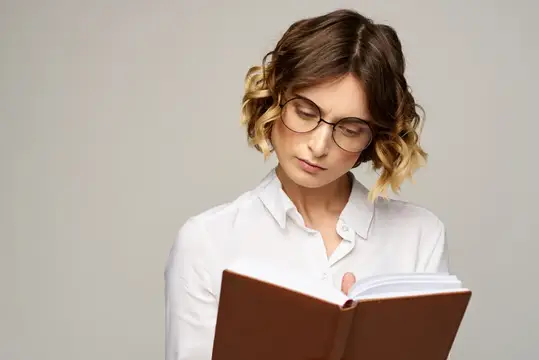 Молодая женщина в очках сосредоточенно читает книгу