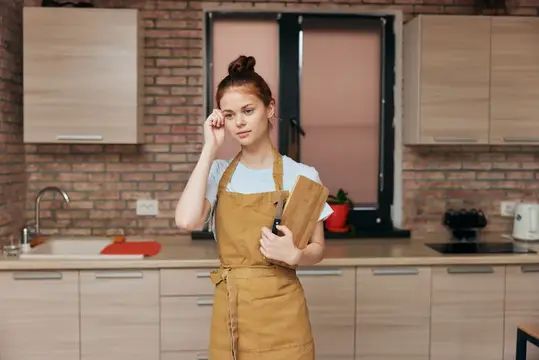 Молодая женщина в фартуке с поварёшкой на кухне