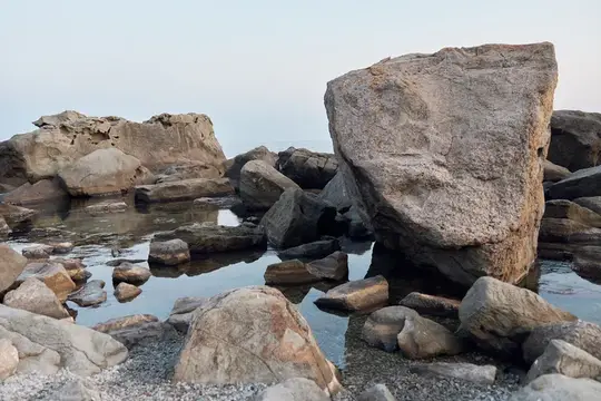 Большие серые валуны среди воды на каменистом берегу