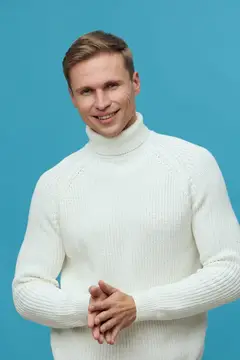 Улыбающийся светловолосый мужчина в белом свитере на голубом фоне