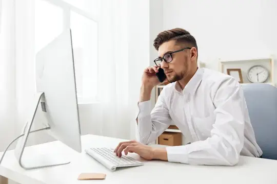Красивый бизнесмен в очках сидит за столом в офисе, работает руководитель