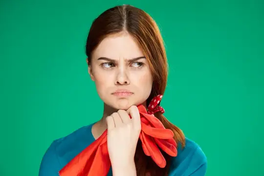Недовольная молодая женщина с красными перчатками на зелёном фоне