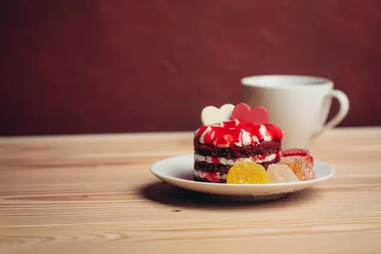 Красный бархатный мини-торт с мармеладом и чашка кофе на деревянном столе