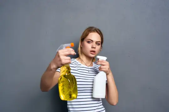 Женщина в полосатой футболке, моющее средство, уборка по дому, серый фон