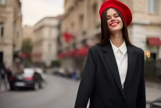 Портрет модной женщины, улыбающейся, стоящей на улице на фоне города