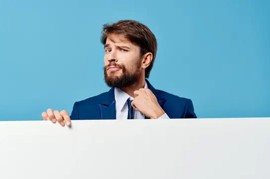 Эмоциональный мужчина с белым рекламным щитом на синем фоне, оставляющим место для текста